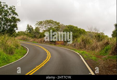 Eine kurvenreiche asphaltierte Straße, die tiefer in den Regenwald auf Kauai führt Stockfoto