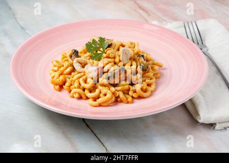 Fideuá auf einem Porzellanteller auf einem Marmortisch serviert Stockfoto