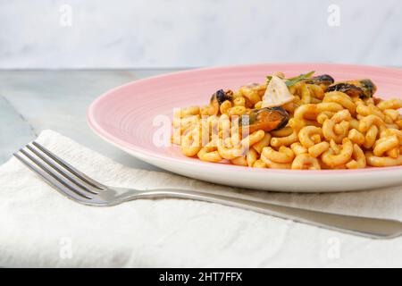 Fideuá auf einem Porzellanteller auf einem Marmortisch serviert Stockfoto