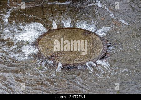 Wasser aus einer Schachtabdeckung, Wilhelmsburg, Hamburg, Deutschland Stockfoto