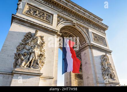 Eine große französische Flagge flattert im Wind unter dem Gewölbe des Triumphbogens in Paris, Frankreich. Stockfoto