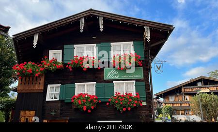 Eine Nahaufnahme eines kleinen Holzgebäudes mit dekorativen Blumen an der Wand auf dem Land Stockfoto