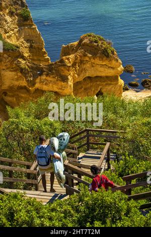 goldgelber Felsen, Klippe und hölzerne Fußgängerbrücke zum wunderschönen Strand Praia do Camilo in der Nähe von Lagos, Algarve, Portugal Stockfoto