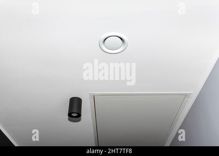 Häusliche mechanische Lüftung mit Wärmerückgewinnung, sichtbarer Abluftanemostat an der Decke im Raum, graue Wand. Stockfoto