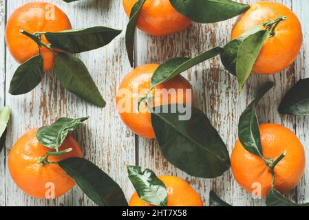 Frische Mandarinen mit Blättern auf Holzgrund Stockfoto