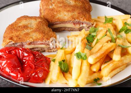 cachopo besteht einfach aus zwei panierten Kalbsfilets, gefüllt mit Käse und Serrano-Schinken mit pommes frites in der Nähe auf dem weißen Teller auf dem Tisch. Hor Stockfoto