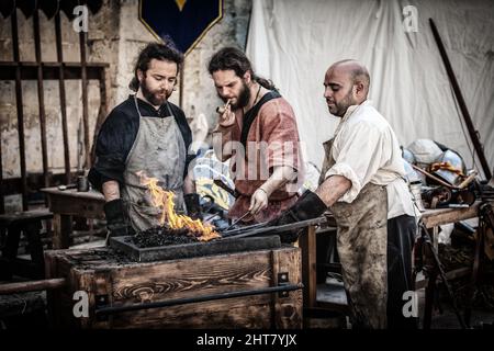 Schwertschmiede, die zu ihrem offenen Kohleofen tendieren Stockfoto