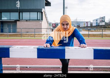 Arabische Frau macht Ausfallschritt-Übung auf der Rennstrecke Stockfoto