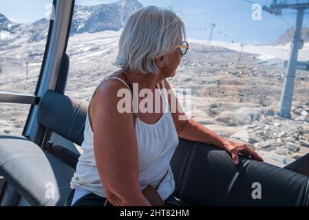 Ältere Frauen blicken von innen in eine Seilbahn in die alpen, Bild vom kitzsteinhorn Gebiet Österreich. Fokus auf Vordergrund. Stockfoto