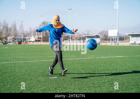 Ethnische Frau spielt Fußball auf dem Sportplatz im Stadion Stockfoto