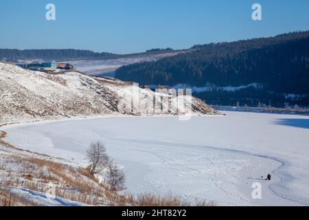 Foto eines Dorfes im Winter, eingebettet zwischen den Bergen auf den Hügeln Stockfoto