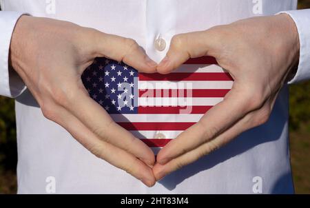 Mann Urlaub seine Hände in herzförmigen auf weißem Hemd mit usa-Flagge Farben nationalen Feiertagskonzept . Stockfoto