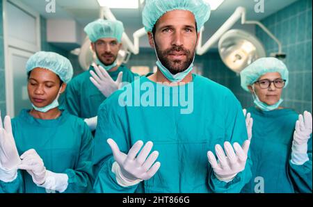 Erfolgreiches Team von Chirurgen stehen im Operationssaal, bereit, an einem Patienten zu arbeiten Stockfoto