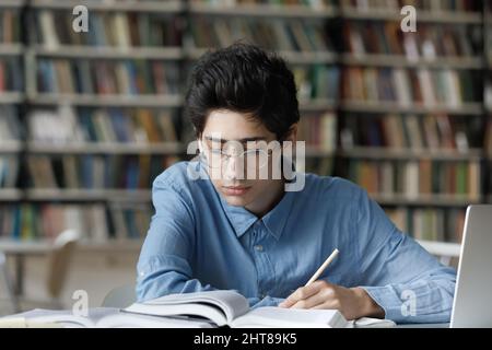 Konzentrierter, beschäftigter junger jüdischer Student, der in der Bibliothek studiert. Stockfoto