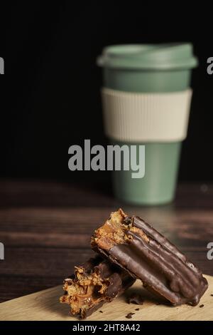 Eine Nahaufnahme eines in Schokolade gefüllten und eingetauchten Churros und einer Tasse Kaffee im Hintergrund Stockfoto