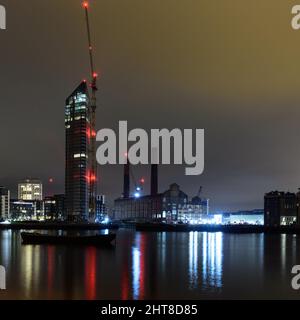 London, England, Großbritannien - 28 Dezember, 2018: Turmdrehkrane in der Nacht beleuchtet sind neben neuen Apartment Gebäude errichten und das verlassene Lots Road Power Station i Stockfoto