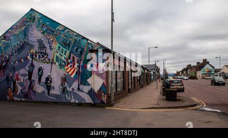 Ein Wandgemälde an der Seite von Geschäften zelebriert die Geschichte der Stadt auf der Invergordon High Street in Schottland. Stockfoto