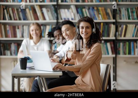 Glückliche junge hispanische Studentin zeigt Daumen nach oben Geste. Stockfoto