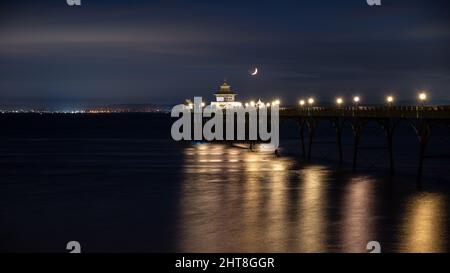 Ein Halbmond untergeht über dem Bristol Channel und dem Clevedon Pier in Somerset, England. Stockfoto