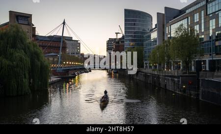 Ein Ruderteam fährt bei Sonnenuntergang am Temple Quay am schwimmenden Hafen von Bristol unter der Valentine's Bridge vorbei. Stockfoto