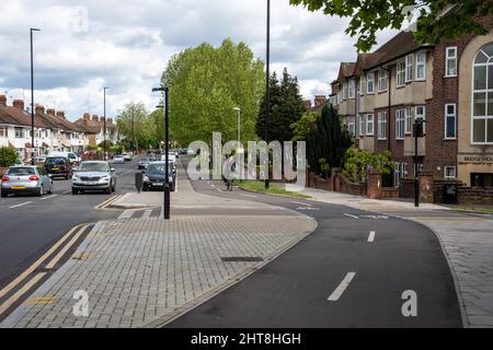 Ein Radfahrer fährt auf einem geschützten Radweg neben einer Straße im Vorort West London. Stockfoto