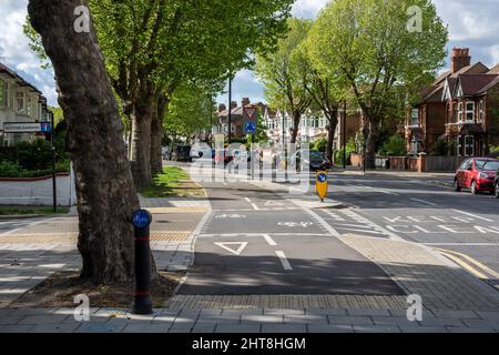 Ein geschützter Radweg kreuzt eine Seitenstraße auf einer Wohnstraße im Vorort West London. Stockfoto