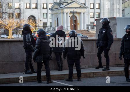 Moskau, Russland. 27. Februar 2022 Polizeibeamte verhaften eine Frau in der Nähe des Gebäudes des Generalstabs der Streitkräfte der Russischen Föderation während eines Antikriegsprotests in Moskau nach Russlands Militäroperation in der Ukraine. Die Inschrift auf der Rückseite lautet „for Peace“ Credit: Nikolay Vinokurov/Alamy Live News Stockfoto