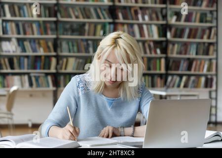 Konzentrierte intelligente asiatische Frau, die in der Bibliothek studiert. Stockfoto
