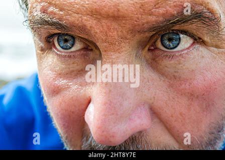 Porträt eines Mannes mit blauen Augen und einem blauen Bluse am Meer Stockfoto