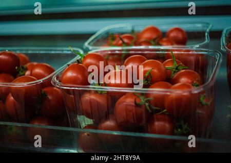 Frische Gartentomaten auf dem Regal einer Supermarktumgebung mit verschwommenem Hintergrund Stockfoto