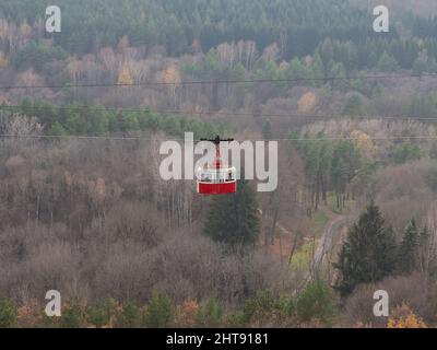 Eine rote Seilbahn im Retro-Stil fährt über einen riesigen Parkbereich. Resort Kislowodsk Park im Herbst Stockfoto