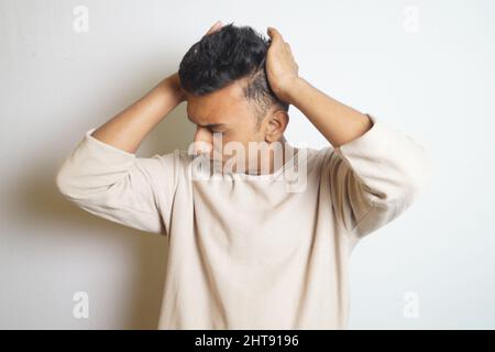 Junger Inder, der seinen Kopf mit geschlossenen Augen hält Stockfoto