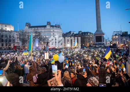 London, Großbritannien. 27.. Februar 2022. Pro-ukrainische Demonstranten halten Fahnen und leuchten auf, während sie auf dem Trafalgar-Platz gegen die russische Invasion in der Ukraine protestieren. Kredit: SOPA Images Limited/Alamy Live Nachrichten Stockfoto