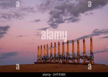 Buntes Klebeband auf den Holzsäulen im heiligen burjat Platz auf Kap Burkhan im Dorf Khuzhir auf der Insel Olchon im Sonnenuntergang Stockfoto