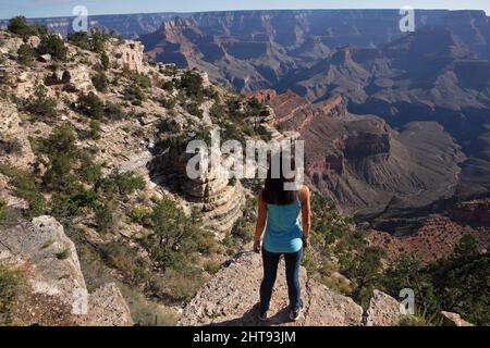 Ein Mädchen blickt auf die Klippen, Felswände und Felsschichten hinunter in die Tiefen des Grand Canyons am Shoshone Point am Südrand. Shoshone Point Stockfoto