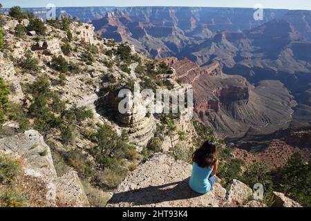 Ein Mädchen blickt auf die Klippen, Felswände und Felsschichten hinunter in die Tiefen des Grand Canyons am Shoshone Point am Südrand. Shoshone Point Stockfoto