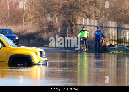 Radfahrer sehen zu, wie ein Fahrzeug auf der Newton Lane in der Nähe von Castleford im Wasser gefangen wurde, nachdem Sturm Franklin viele Teile Großbritanniens überschwemmt hatte Stockfoto