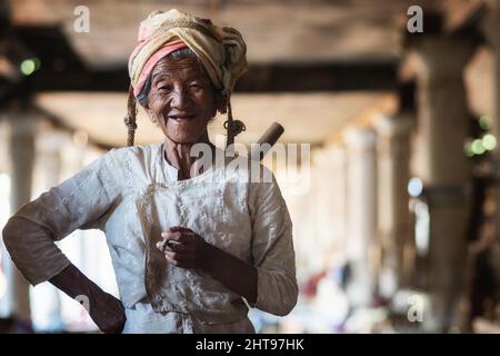 Eine alte burmesische Dame raucht eine Zigarre auf dem traditionellen Handwerksmarkt im Dorf Indein, Shan State, Myanmar (Burma). Stockfoto