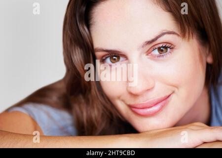 Nahaufnahme einer eleganten Brünette mit einem sanften Lächeln. Nahaufnahme Porträt einer schönen weiblichen Brünette mit einem charmanten Lächeln. Stockfoto