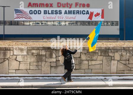 Detroit, Michigan, USA. 27.. Februar 2022. Eine Frau trägt eine ukrainische Flagge, als sie auf eine Kundgebung zugeht, die gegen die russische Invasion in der Ukraine protestiert. Fast 40.000 Einwohner von Michigan sind ukrainischer Abstammung. Kredit: Jim West/Alamy Live Nachrichten Stockfoto