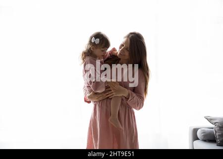 Glücklich schwanger Mutter hält ältere kleine Tochter Mädchen in den Armen Stockfoto