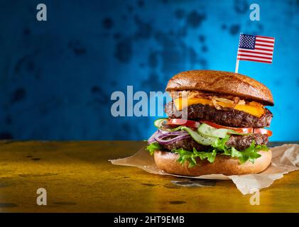 Köstlicher Doppel-Burger mit Rinderschnitzel und frischem Gemüse auf Pergamentpapier Stockfoto