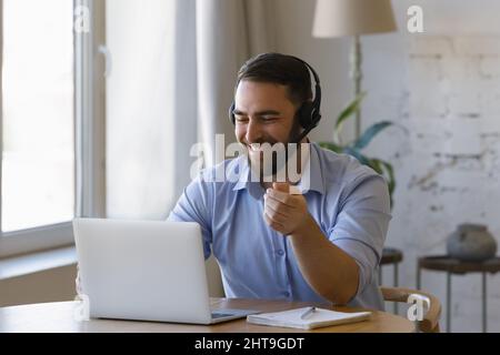 Der Mann trägt ein Headset, wenn er mit einem Laptop von zu Hause aus arbeitet Stockfoto