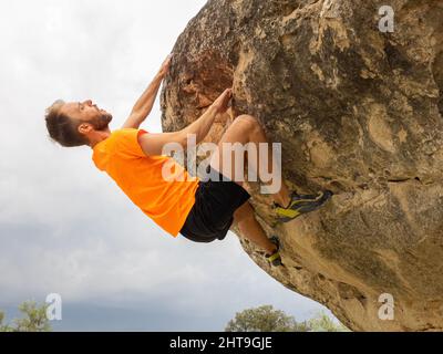 Junger Kaukasier klettert auf Steinfelsen, Konzept Bouldern Stockfoto