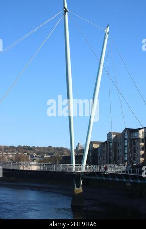 Lune Millennium Bridge, eine Fußgängerbrücke über den Fluss Lune in Lancaster, Lancashire, mit Ashton Memorial auf der Skyline zwischen den Masten der Brücke. Stockfoto