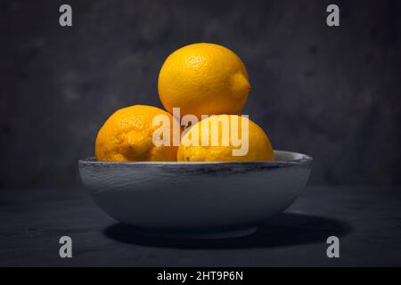 Ein Nahaufnahme-Studiofoto von ganzen Zitronen in einer Holzschale. Stockfoto