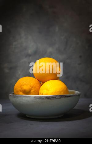 Ein Nahaufnahme-Studiofoto von ganzen Zitronen in einer Holzschale. Stockfoto