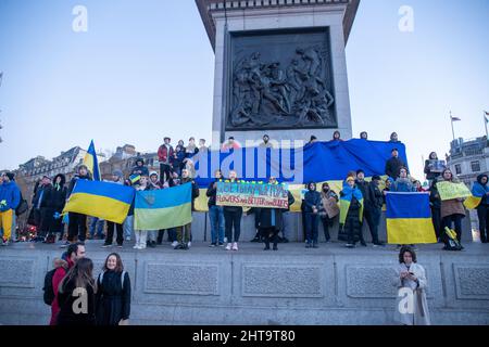 LONDON, FEBRUAR 27 2022 Pro-ukrainische Demonstranten halten die ukrainische Flagge auf der Nelson-Kolonne, während sie auf dem Trafalgar-Platz gegen Russlands Invasion der Ukraine protestieren. Kredit: Lucy North/Alamy Live Nachrichten Stockfoto