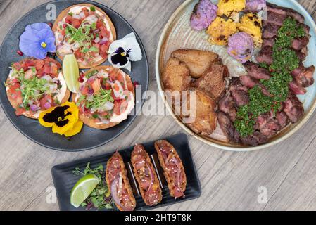 Familienbuffet mit Ribeye Steak, Ceviche Tacos oder knusprigen Ahi Poke Tacos zur Auswahl. Stockfoto