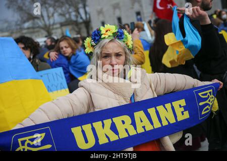 Istanbul, Türkei. 27.. Februar 2022. Ein Protestler mit einer Krone aus blauen und gelben Blumen hält während der Demonstration gegen die russische Aggression einen Schal mit dem Wort Ukraine auf. Am vierten Tag des Angriffs russischer Truppen auf die Ukraine versammelten sich ukrainische Bürger und Antikriegsdemonstranten auf dem Beyazit-Platz in Istanbul, um gegen Russland und den russischen Präsidenten Wladimir Putin zu protestieren. (Foto von Hakan Akgun/SOPA Images/Sipa USA) Quelle: SIPA USA/Alamy Live News Stockfoto